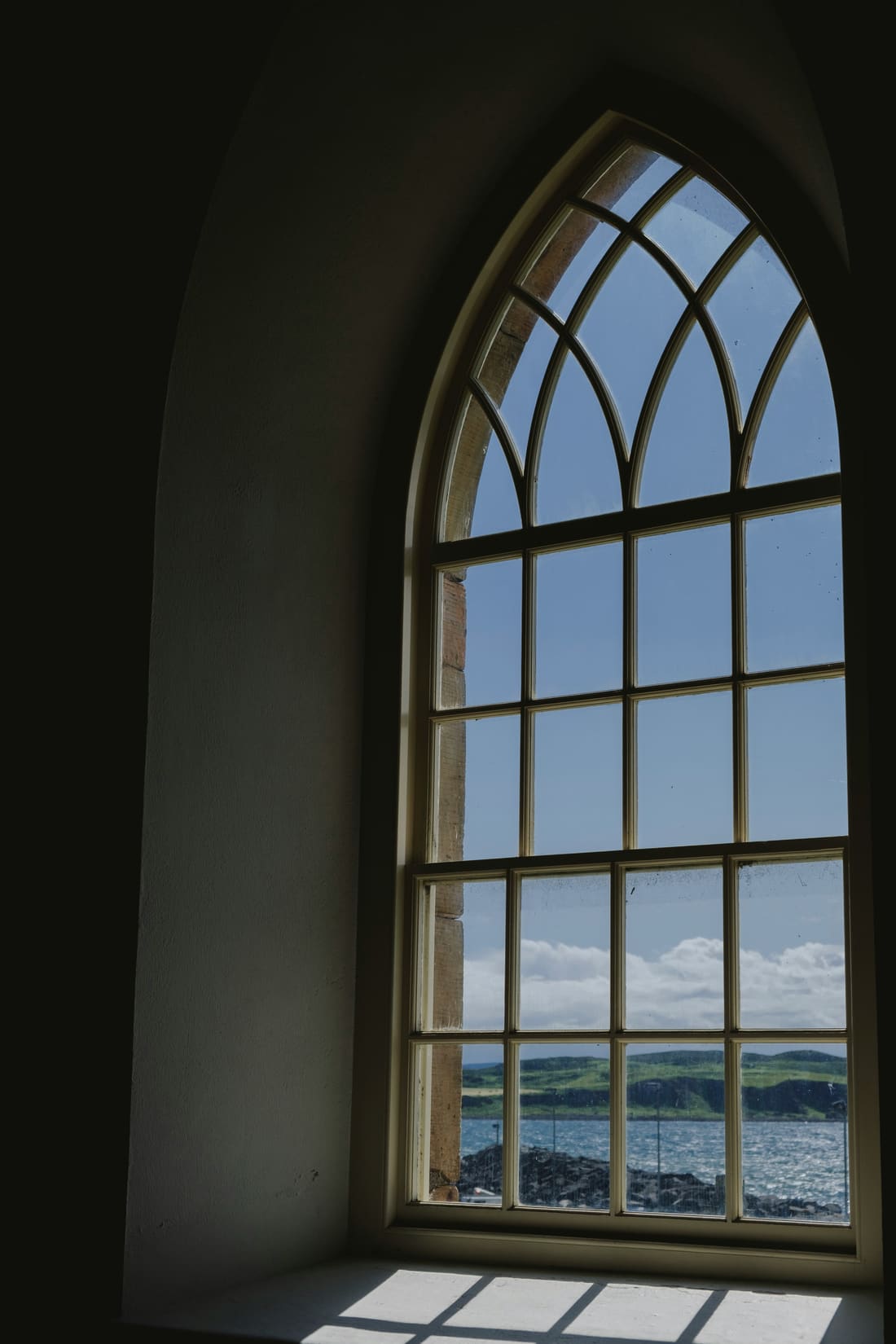 Sunlight through an arched window opening onto the sea